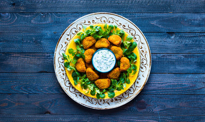 Chicken nuggets with yogurt sauce on a wooden background
