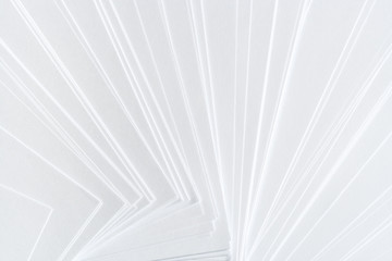 White geometric background from a lot of clean paper sheets laid out carelessly as fan.