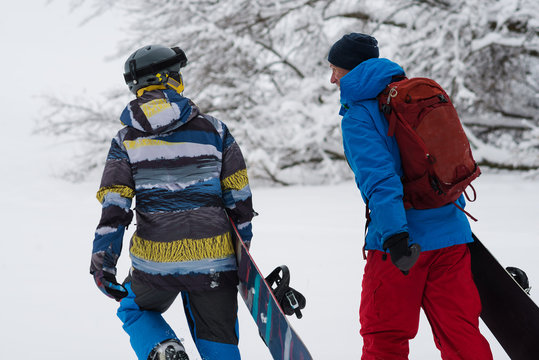 Two happy snowboarders is walking, talking and laughing
