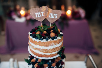 Naaked wedding cake with blueberries, raspberries and mint, two heart form plates on the top