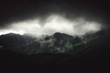Stormy alpine landscape with fog and grey cloud
