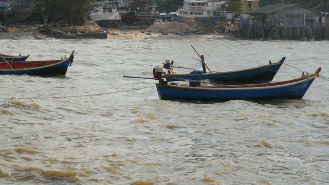 Small fishing boats sail along the lush sea on waves. Fishermen catch fish in the sea