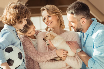 young family with adorable labrador puppy in front of cardboard house