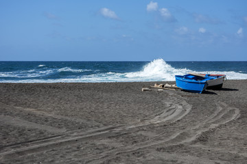 Niebieska łódka na czarnej plaży