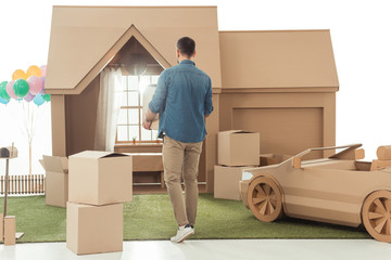 rear view of man with boxes moving into new cardboard house isolated on white