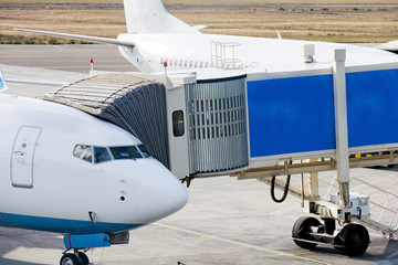 Jetway is served to passenger airplane at airport. Close up. Preparation for departure, boarding passengers on board.