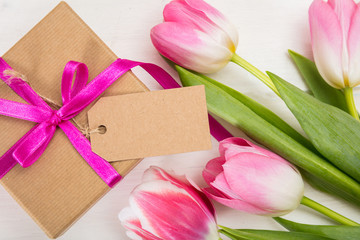 Fototapeta premium Mothers day. Pink tulips and a blank card gift on white background, top view, copy space