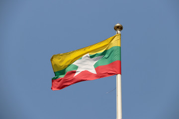 National flag of Myanmar on bright blue sky background. Blown away by wind. Myanmar is one of the ten Association of South East Asian Nations.