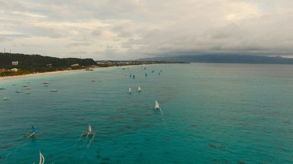 Naklejka premium Aerial view: Boracay, Sunset over the sea in the background boats,sailing boat, orange sky and islands.Tropical beach at sunset. Sailing boats at sunset in the sea. White sand beach. Travel concept