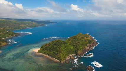 Coast of the tropical island Catanduanes with the mountains and the rainforest on a background of ocean with big waves. Aerial view: sea and the tropical island with rocks, beach and waves. Seascape