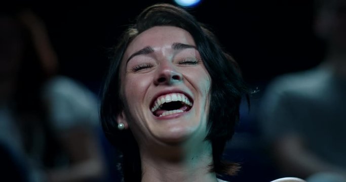 Woman laughing uncontrollably while watching a comedy movie at the cinema