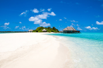 Fototapeta na wymiar Beautiful sandy beach and over water tropical bungalo