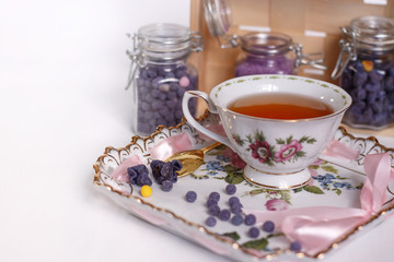 beautiful Cup of black tea on a ceramic tray with pieces of sugar from violets