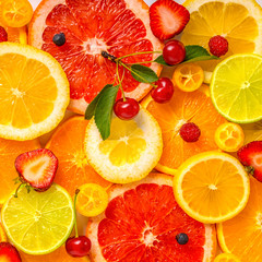 Obraz na płótnie Canvas beautiful fresh sliced mixed citrus fruits as background with different berries, concept of healthy eating, dieting, top down