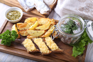 Herring in a jar with fried potato on wooden board