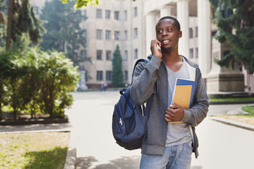 Obraz premium Happy african-american student talking on smartphone in campus