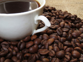 Coffee cup and roasted coffee beans on burlap
