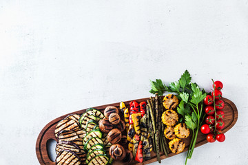grilled vegetables on a wooden tray on a white stone table. copy space, overhead shot