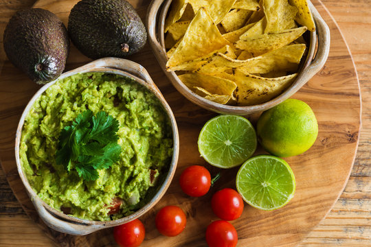 Guacamole dip with avocados limes tomatoes and tortilla chips