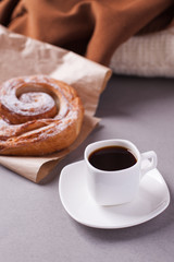 a cup of espresso on a saucer and a layered bun - a classic breakfast of a European or North American