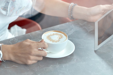 Woman looking at touch pad screen while standing in cafe