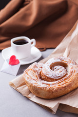 a cup of espresso on a saucer and a layered bun - a classic European or North American breakfast and a love letter in an envelope