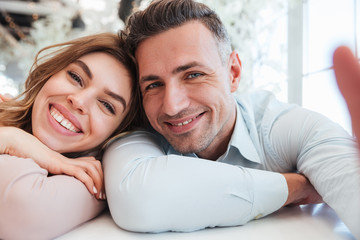 Two cute people man and woman having fun together, and making beautiful selfie while having lunch break in restaurant