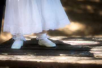 Child feet in shoes on a dark wood