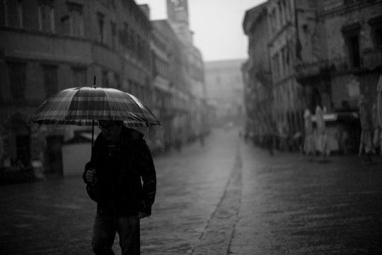 Passeggiare con ombrello sotto la pioggia in città