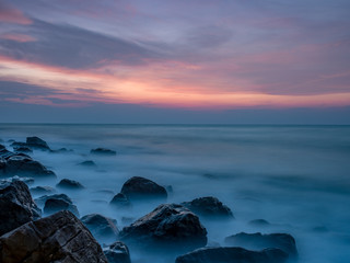 Fototapeta premium first light at the rock beach with smooth wave 