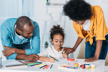 african american parents helping daughter drawing at home