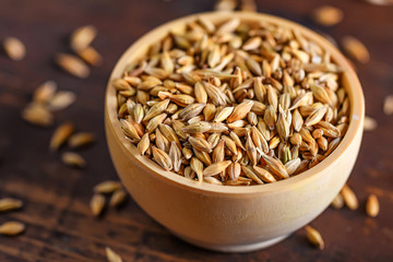 Barley grain in wooden bowl on wooden table