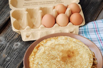 Fresh pancakes and eggs on a wooden table 