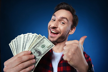 Handsome bearded man in red shirt. Funny guy is a lucky winner, she is holding a pile of money, he is surprised and can't believe it, he is happy to win one million dollar jackpot, now he is rich.