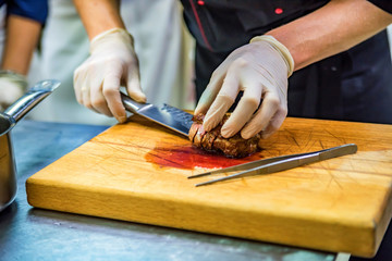 Chef hands slice delicious steak on wooden board
