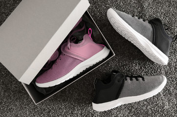 Pairs of violet, black and white sneakers in shoe cardboard box on gray background. Active running...