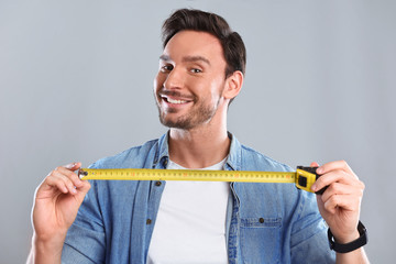 Handsome bearded man with a Tape measure is happy and isolated on a white background. Guy with...