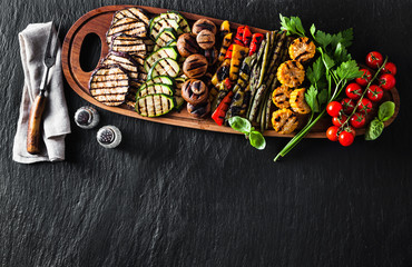 grilled vegetables on a wooden tray on a black slate. copy space
