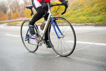 Fototapeta na wymiar Young Woman Riding Road Bicycle on the Highway in the Cold Autumn Day. Healthy Lifestyle.