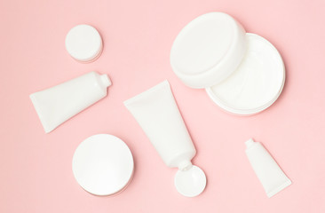 White cosmetic tubes and cream containers top view on pink background - 192032152