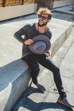 Happy hipster man holding hat in the street