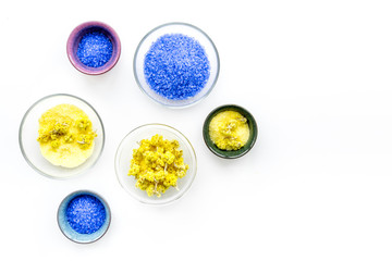 Colorful spa salt. Yellow spa salt with delicate spring flowers and violet lavender spa salt on white background top view copy space