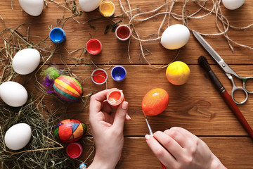 Painting colorful easter eggs, top view on wood