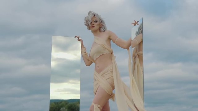 young and beautiful woman with a thin figure, looking like an alien resident holding a mirror in her hands, a lady with gray hair shows the reflection of an oasis in the glass