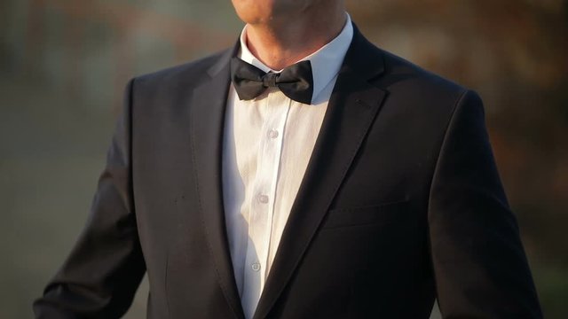 Handsome groom fixes his Bow Tie and jacket. Slow motion