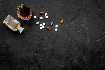 Hungover syndrome. Alcoholism. Glass and pills on black background top view copy space