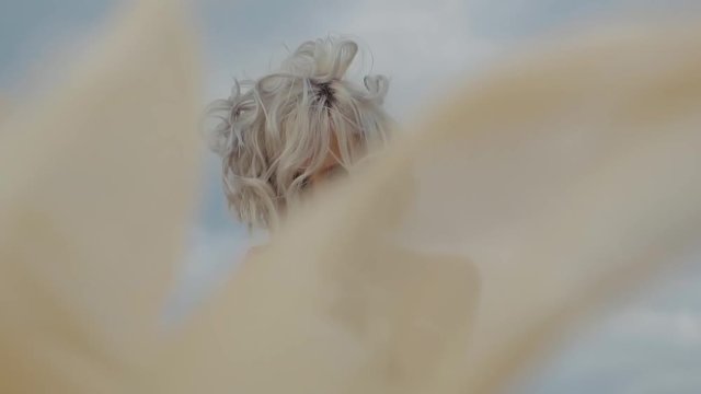 portrait of a beautiful woman with gray hair, who plays with her clothes, the cloth flutters in the wind, the mysterious lady is in the daytime outdoors