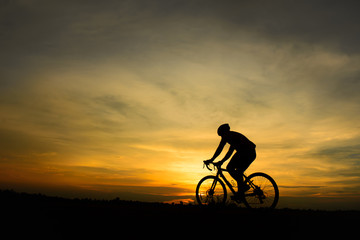 Obraz na płótnie Canvas Silhouette of handsome man with bicycle on sunset,sport man concept
