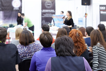 Fototapeta premium Rear view from the back of a group of girls students at a presentation, training on hair care.