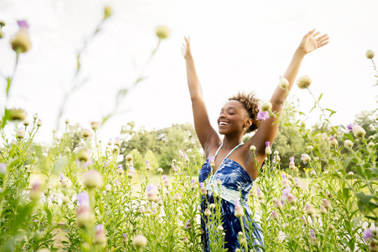 Smiling mixed race woman celebrating in field of wildflowers